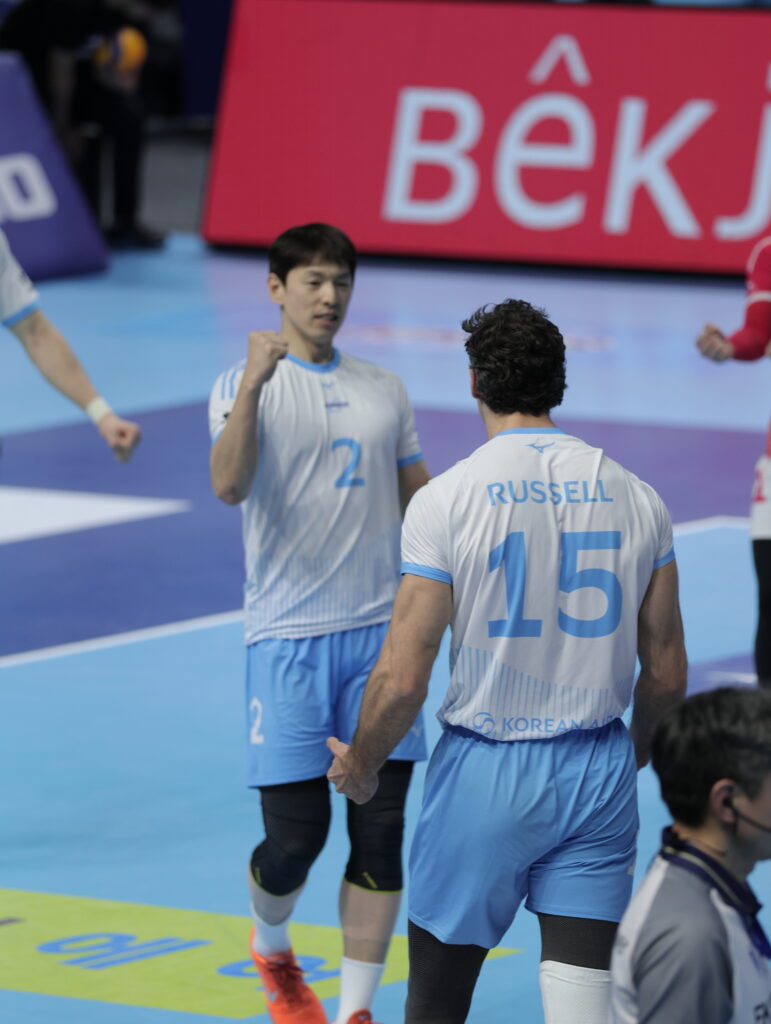 Volleyball players celebrating teamwork on the court during a match.